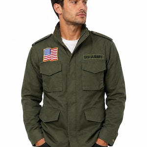 Puede incluir: Chaqueta verde oliva de estilo militar con un parche de la bandera estadounidense y el texto "US ARMY". La chaqueta tiene cremallera, múltiples bolsillos y charreteras. Se lleva sobre una camiseta blanca.