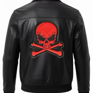 May include: Black leather jacket featuring a red skull and crossbones patch on the back. The jacket has a classic collar, a zip-up front, and a ribbed hem and cuffs. A stylish outerwear piece.