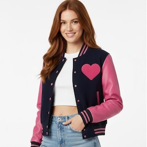 May include: A navy blue varsity jacket with pink leather sleeves and a pink heart emblem. The jacket features a button-up front, striped cuffs, and a ribbed collar. A fashionable outerwear item.