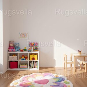 May include: A colorful, flower-shaped rug with a rainbow design, featuring pink, purple, blue, green, and orange hues. The rug is placed on a wooden floor in a room with a white bookshelf, toys, and a small table and chairs. The room is well-lit.