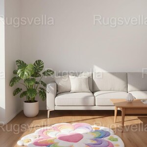 May include: A colorful, flower-shaped rug with a white base and rainbow-colored petals. The rug features a heart-shaped center and is placed on a wooden floor in a living room setting. The room includes a white sofa, a potted plant, and a small wooden table.