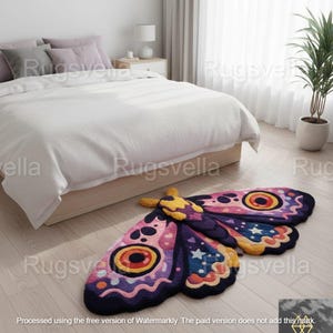 May include: A colorful moth-shaped rug with a whimsical design. The rug features pink, purple, yellow, and blue hues with star and eye motifs. It is placed on a light wood floor near a bed.