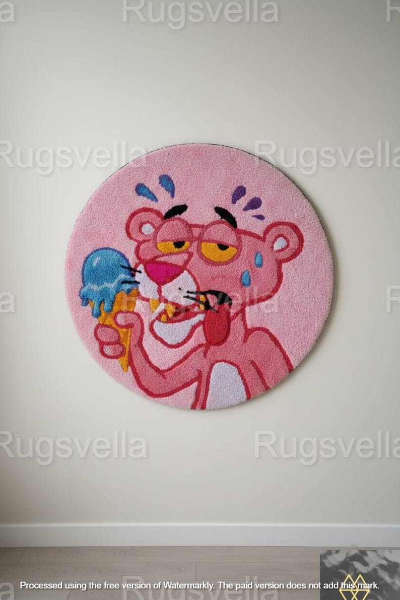 Op de afbeelding: Een roze ronde vloerkleed met een cartoonafbeelding van de Roze Panter die een blauw ijsje vasthoudt. De Roze Panter zweet, draagt een gele bril en steekt zijn tong uit. Een leuk decoratief item.