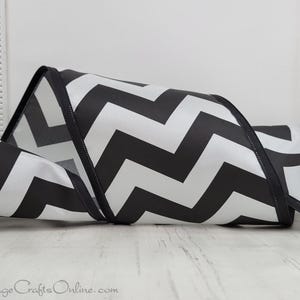 May include: Black and white chevron patterned ribbon. The ribbon is folded in a loop and has a satin finish.