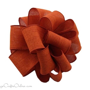 May include: A large, rust-colored burlap bow with a textured, woven finish. The bow is made of multiple loops of ribbon, creating a full and voluminous look.