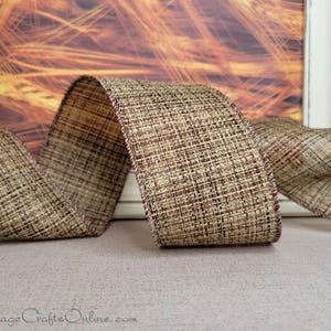 May include: A roll of brown and beige burlap ribbon with a subtle woven texture. The ribbon has a brown edge and is perfect for crafting and decorating.