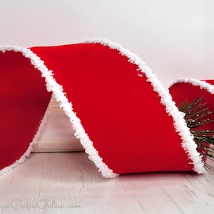 May include: Red velvet ribbon with a white fuzzy trim. The ribbon is curled and twisted, showing off the texture of the fabric.