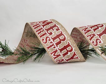 May include: A tan burlap ribbon featuring the red text MERRY CHRISTMAS with white outlines and small white polka dots. The ribbon is woven through green artificial pine branches that have a light dusting of white glitter on the needles.