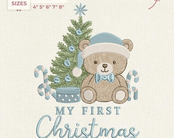 May include: An embroidery design featuring a teddy bear wearing a blue hat and bow tie, next to a Christmas tree and candy canes. The text "MY FIRST Christmas" is displayed in a script font. Sizes available: 4", 5", 6", 7", 8".