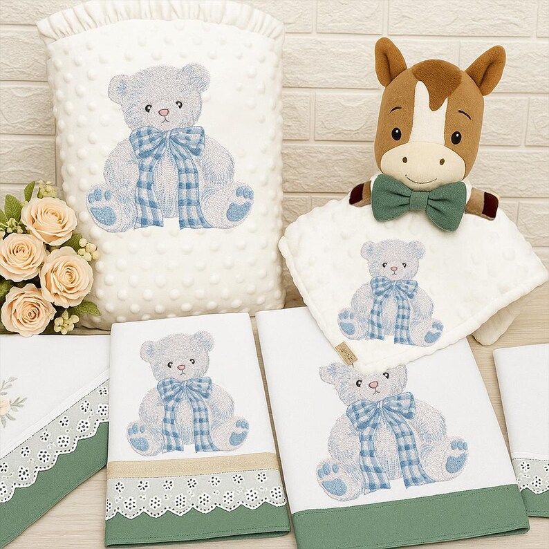 May include: A collection of baby items featuring a teddy bear design. The set includes a white, textured blanket, several white towels with green trim and lace, and a plush horse toy. The teddy bear has a blue plaid bow.