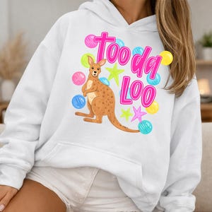 K&ouml;nnte beinhalten: Wei&szlig;er Kapuzenpullover mit einem K&auml;nguru-Motiv und dem pinkfarbenen Text "Too da Loo". Das K&auml;nguru ist braun und das Design umfasst bunte Sterne und Blasenakzente.