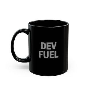 May include: Black ceramic coffee mug with the text "DEV FUEL" in white block letters. The mug has a curved handle and a glossy finish. The mug is designed for hot beverages.