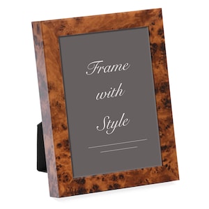 May include: A rectangular picture frame with a brown, wood-grain finish. The frame has a dark gray interior with the words "Frame with Style" in white script. A black stand is attached to the back.