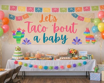 May include: A festive baby shower scene with colorful balloons, a banner reading "Let's Taco 'bout a baby," and a table laden with treats. Decorations include a cactus and piñata.