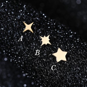 May include: Three small gold-toned star-shaped studs labeled A, B, and C. Stud A is a four-pointed star, stud B is a four-pointed star with sharper points, and stud C is a classic five-pointed star. Each piece has a smooth, polished finish.
