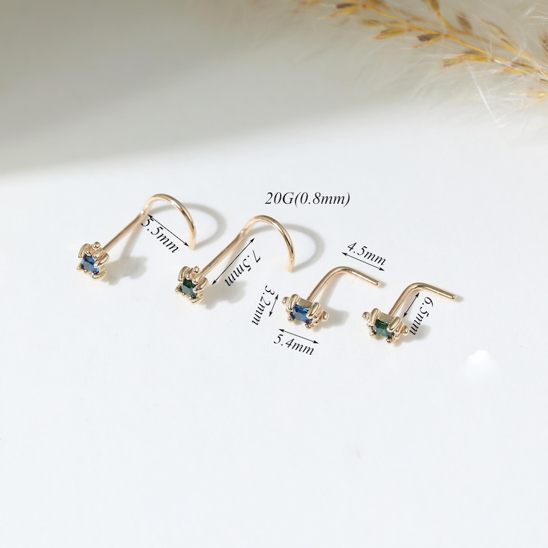 May include: Four gold-tone nose studs with square-cut blue and green gemstones. The studs feature a 20G (0.8mm) gauge. Labeled dimensions include 5.5mm, 7.5mm, 3.2mm, 5.4mm, 4.5mm, and 6.5mm, indicating various post lengths and stone settings.