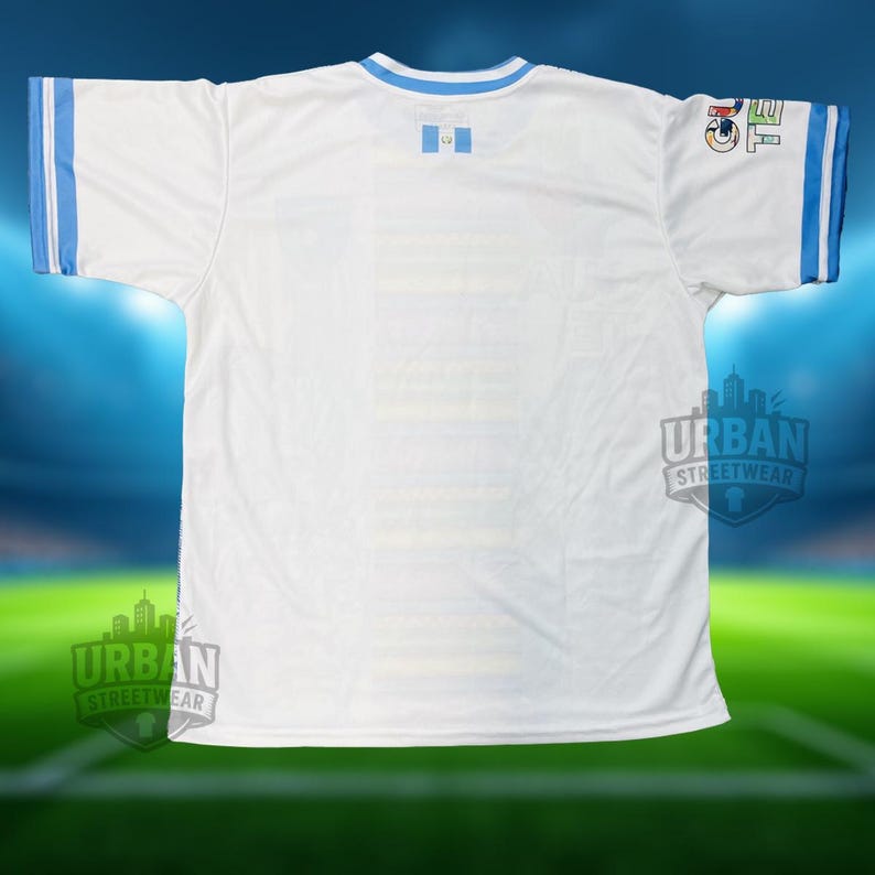 May include: White football shirt with light blue trim on the collar and sleeves. Includes a Guatemalan flag emblem and a sleeve logo. The shirt displays the "Urban Streetwear" logo.