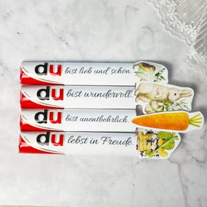 May include: Four white and red candy bars with German text and Easter-themed illustrations. The text includes phrases like "you are lovely" and "you are wonderful."
