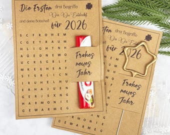 Könnte beinhalten: Zwei braune Papierkarten mit deutschem Text und einem Schokoriegel. Eine Karte hat ein Wortsuchrätsel und den Text "Frohes neues Jahr". Die andere Karte hat eine sternförmige goldene Büroklammer.