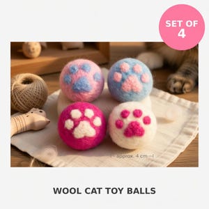 Può includere: Un set di quattro palline giocattolo in lana per gatti, ognuna con un design a zampa in feltro a contrasto. Le palline sono colorate in rosa, azzurro, magenta e bianco. Un indicatore di misura sull'immagine mostra un diametro di circa 4 cm.