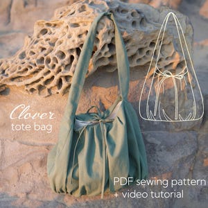 May include: A sage green Clover tote bag with long straps, tied at the top. The bag is made of soft fabric and is displayed against a textured rock background. Text on the image reads "Clover tote bag" and "PDF sewing pattern + video tutorial."