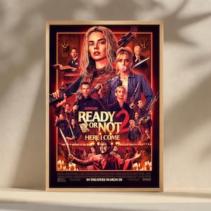 Könnte beinhalten: Ein gerahmtes Filmplakat für "Ready or Not 2: Here I Come". Das Poster zeigt eine Collage von Schauspielern, Waffen und dem Filmtitel in fetten Buchstaben. Die Farbpalette wird von Rot, Orange und Schwarz dominiert.