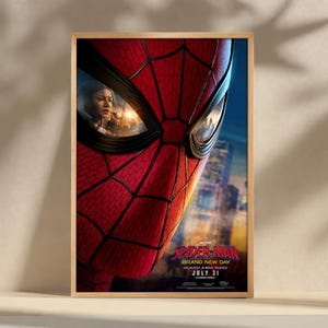 Peut inclure: Affiche de film encadrée avec un gros plan du masque de Spider-Man, avec des toiles d'araignée rouges et des accents noirs. L'affiche comprend le texte "Spider-Man Brand New Day" et "July 31". Une vue de la ville est visible en arrière-plan.