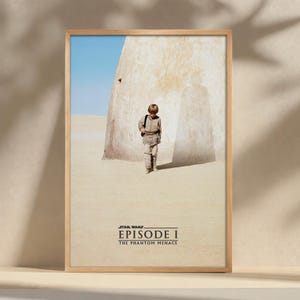 Puede incluir: Póster enmarcado de Star Wars Episodio I con un niño caminando por un paisaje desértico. El póster tiene un marco de madera marrón claro. El título "Episode I The Phantom Menace" está impreso en la parte inferior.