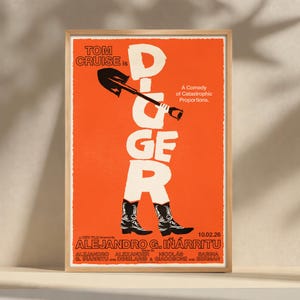 May include: A framed movie poster with an orange background. The poster features the title "Digger" in large white letters, with a shovel incorporated into the "G". The poster also includes the text "Tom Cruise is" and "A Comedy of Catastrophic Proportions."