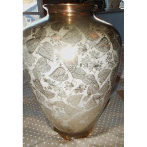 May include: A large, decorative vase with a wide base and a narrow neck. The vase is white with a gold leaf pattern and a gold rim. The leaf pattern covers the entire surface of the vase.