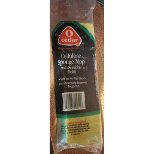 Puede incluir: Un paquete que contiene un recambio de mopa de esponja de celulosa amarilla con un estropajo. El embalaje es negro con la marca "cedar" y los detalles del producto. El texto en el paquete indica que es seguro para suelos sin cera y elimina la suciedad difícil.