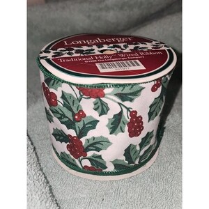 May include: A spool of Longaberger Traditional Holly wired ribbon featuring a white background with a repeating pattern of green holly leaves and red berries. The top label includes the text Longaberger Traditional Holly Wired Ribbon.