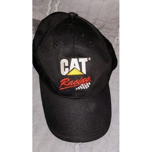 Peut inclure: Une casquette de baseball noire avec le texte brodé blanc CAT, un logo triangle jaune au-dessus du mot Racing brodé en rouge, et un petit motif de drapeau à damier blanc et noir situé sous le texte sur le panneau avant.