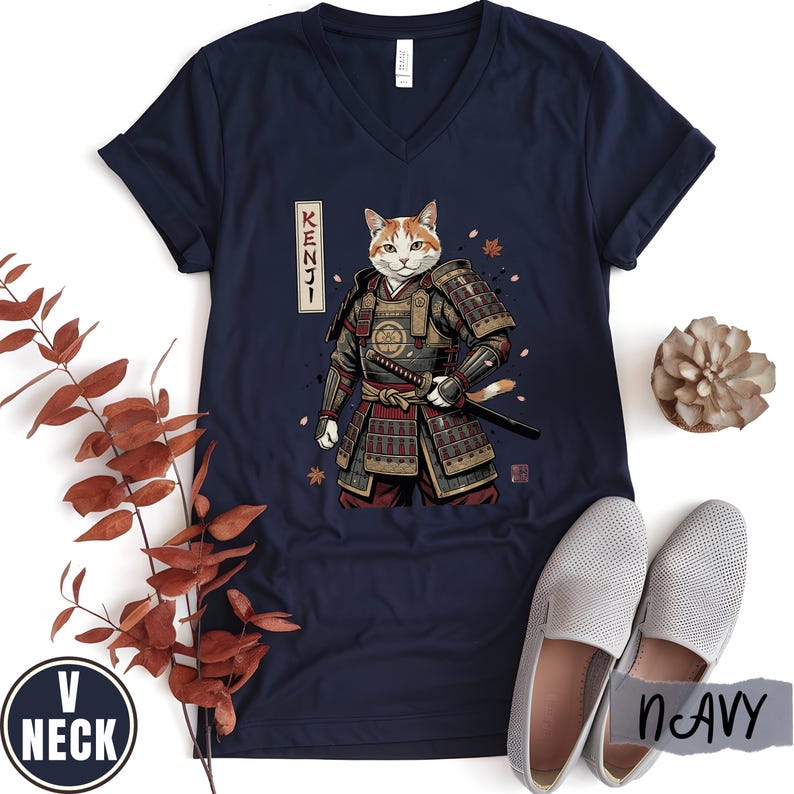 Puede incluir: Camiseta azul marino con cuello en V con una ilustraci&oacute;n de un gato con armadura de samur&aacute;i, sosteniendo una katana. El gato tiene pelaje naranja y blanco. La palabra "KENJI" est&aacute; impresa verticalmente a la izquierda. La camiseta tiene una etiqueta "V NECK".