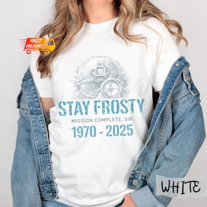 May include: White t-shirt with a blue graphic that reads "STAY FROSTY" above "MISSION COMPLETE, SIR." and the years "1970 - 2025." The graphic features a vintage diving helmet and compass design.