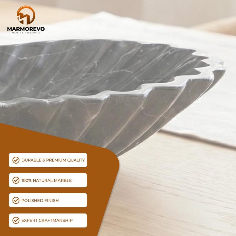 May include: A gray marble decorative bowl with a fluted design. The bowl is made of natural marble and has a polished finish. The image also includes the text "MARMOREVO Marble & Handicrafts".