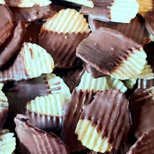 May include: A collection of ridged potato chips partially dipped in smooth dark chocolate. Each chip features a distinct wavy texture with a visible contrast between the golden-yellow potato surface and the glossy, dark brown chocolate coating.