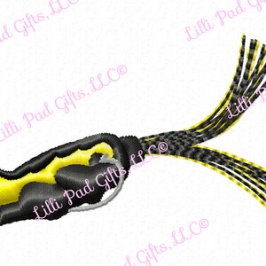 May include: A black and yellow frog lure with a long, black and yellow tail. The lure is designed to resemble a frog.