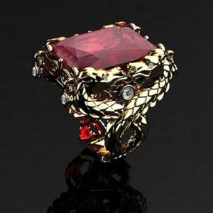 Puede incluir: Un anillo dorado con una gran gema roja rectangular. El diseño del anillo incorpora intrincados motivos de dragones o serpientes, con pequeñas gemas claras. El anillo se encuentra sobre un fondo oscuro.
