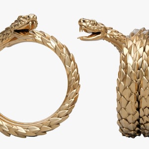 May include: Gold-coloured snake ring and bracelet set. The ring is a complete circle with a snake head at the top. The bracelet is a coiled snake with its head raised. Both pieces have a textured, scale-like design.