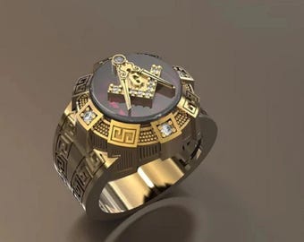 Puede incluir: Un anillo dorado con un emblema masónico con un diseño de compás y escuadra. El anillo tiene una piedra central de color rojo oscuro y está adornado con pequeñas gemas transparentes. La banda tiene un patrón geométrico detallado.