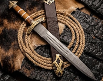 May include: A detailed image of a Viking-style sword with a wooden handle and a metal blade. The sword is displayed with its leather sheath, a coiled rope, and a backdrop of charred wood and animal hide. The sword's hilt and sheath feature intricate gold-colored metalwork.