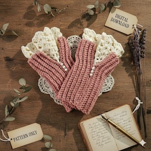 Könnte beinhalten: Ein Paar rosa gehäkelte Fingerhandschuhe mit Perlenakzenten, die auf einer cremefarbenen Spitzendecke liegen. Die Handschuhe befinden sich auf einer Holzoberfläche, mit einem Etikett mit der Aufschrift "PATTERN ONLY". Ein Vintage-Notizbuch und ein Stift sind ebenfalls sichtbar.