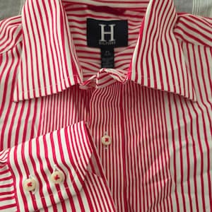 May include: A red and white striped button-down shirt with a pointed collar and buttoned cuffs. The shirt features the "H" Hilfiger logo on the label. The shirt is a medium size.