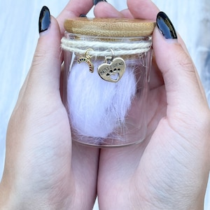 May include: A clear glass jar with a bamboo lid contains white pet fur. Two charms hang from the lid: a rainbow charm and a silver heart charm with the words "Best Friend".