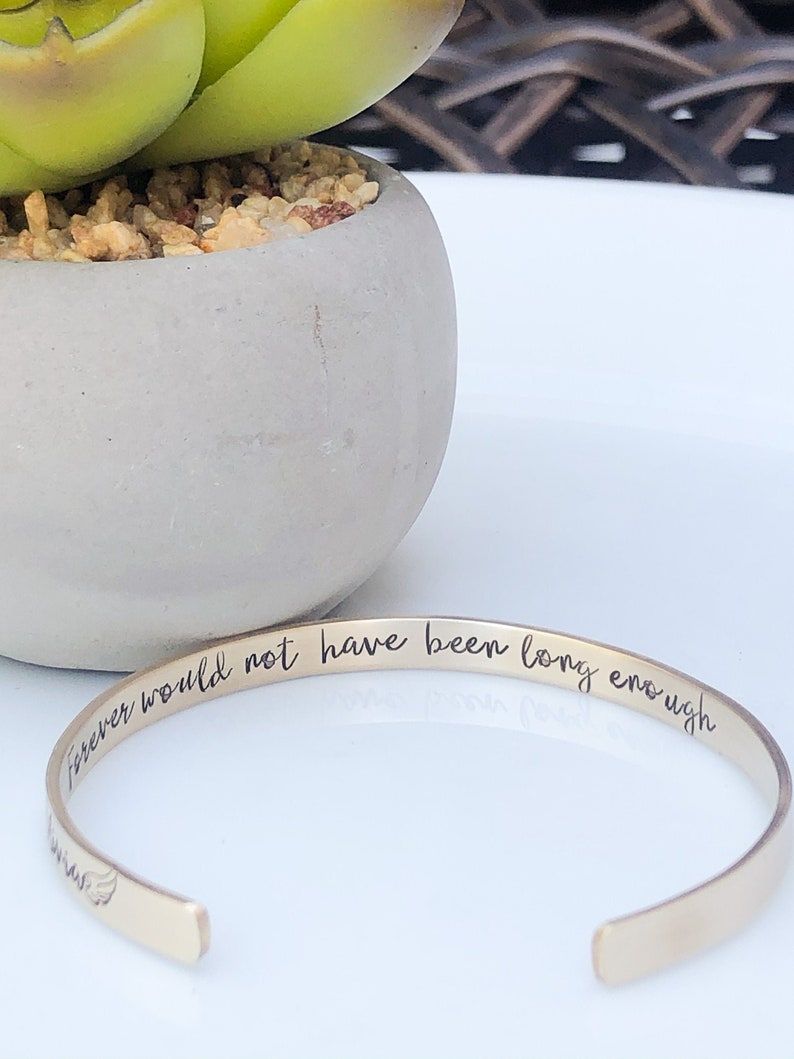 May include: Gold bangle bracelet with the inscription "forever would not have been long enough".