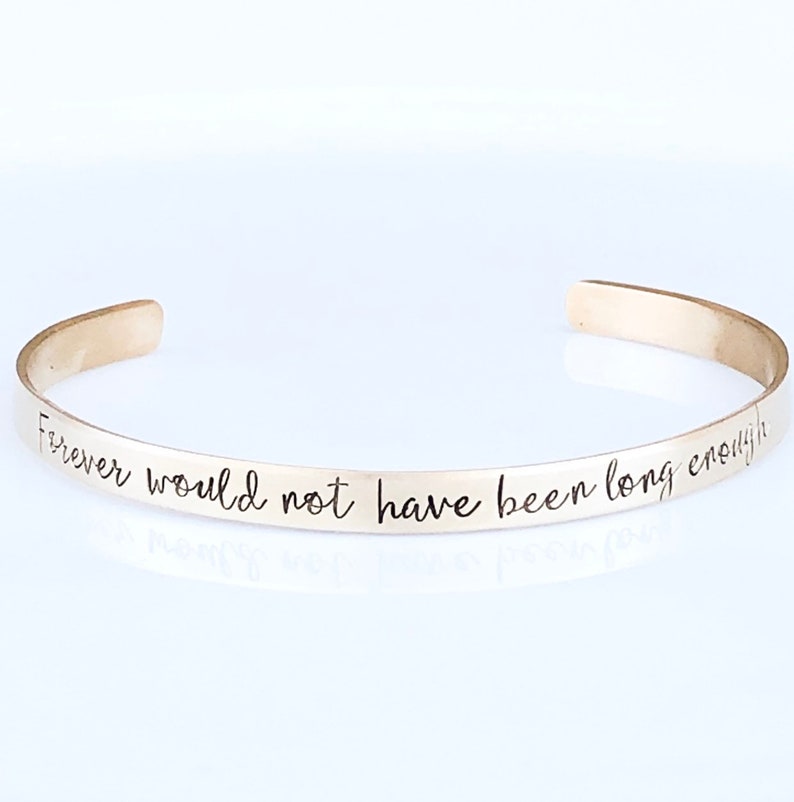 May include: A silver bangle bracelet with the inscription "Forever would not have been long enough".