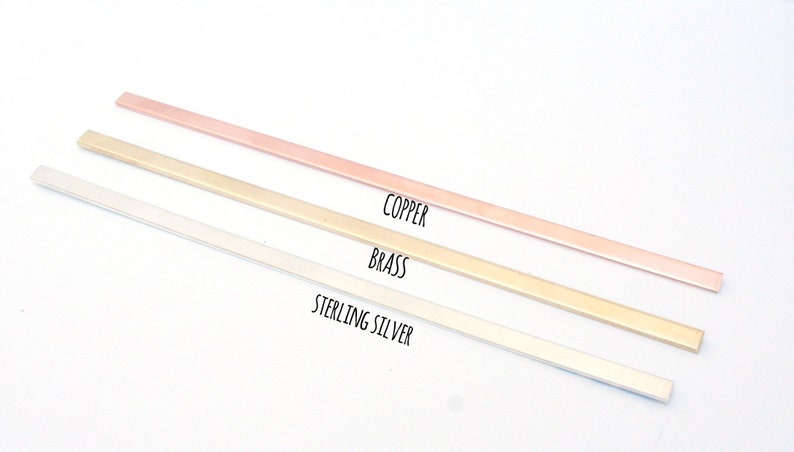 May include: Three metal strips in different colors: copper, brass, and sterling silver. The strips are arranged vertically, with the copper strip at the top and the sterling silver strip at the bottom.