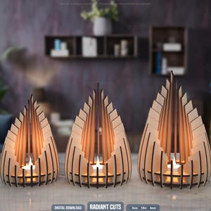 Op de afbeelding: Drie houten kandelaars met een geometrisch ontwerp. Elke houder heeft een unieke vorm en grootte, met verticale houten latten en een centrale ruimte voor een brandende kaars. De warme gloed van de kaarsen verlicht de houten structuur. De tekst "RADIANT CUTS" staat onderaan.