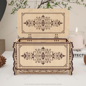May include: A wooden decorative box with an open lid, featuring intricate floral and geometric patterns. The box is light brown with dark brown etched designs. The lid is open, revealing the interior. The box is on a white surface.